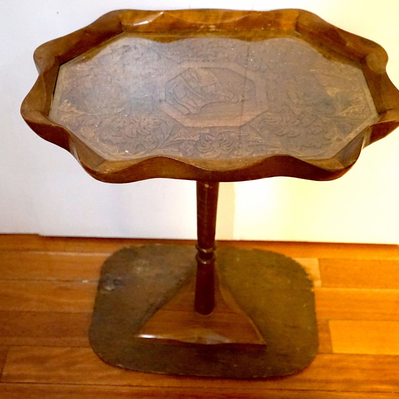 A stand or table  with a carved top and triangular base 